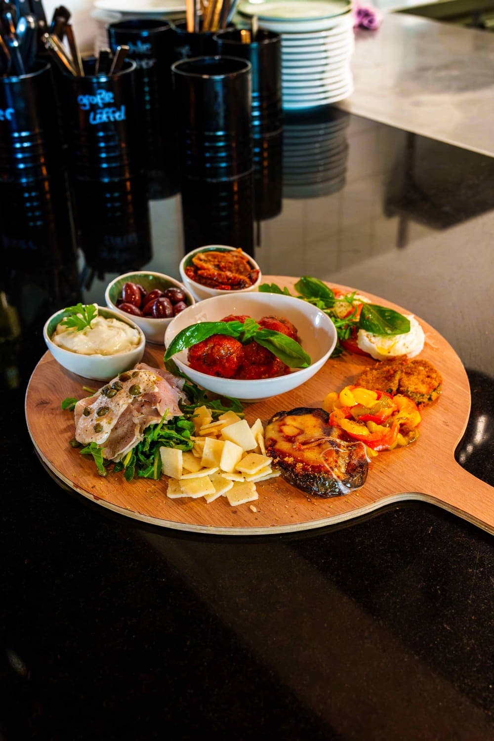 Antipasti-Brett mit Vitello, Pecorino, Fleischbällchen, Oliven, Mozzarella und gebackenem Gemüse