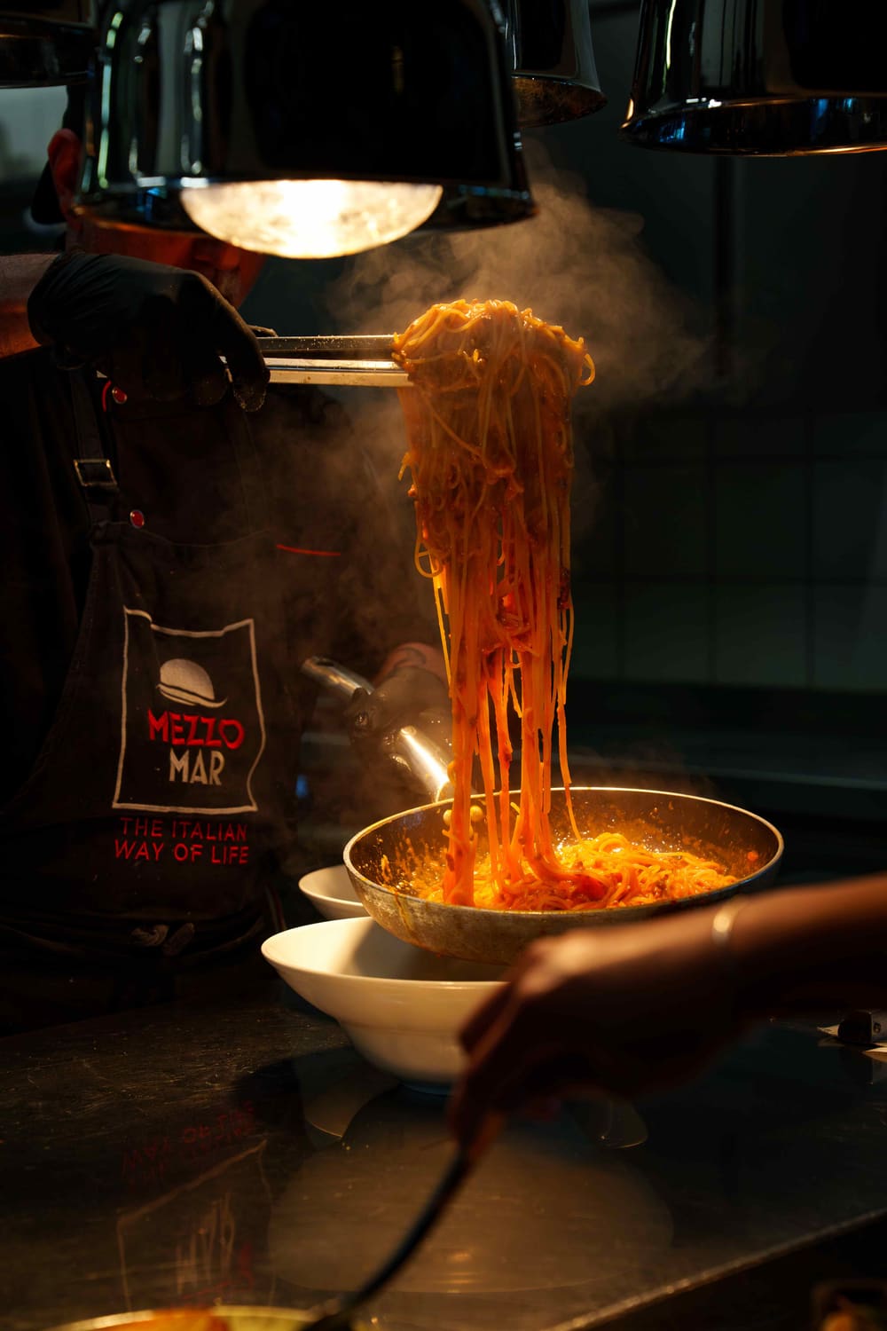 Dampfende Spaghetti mit Sauce werden in der Küche aus der Pfanne gehoben
